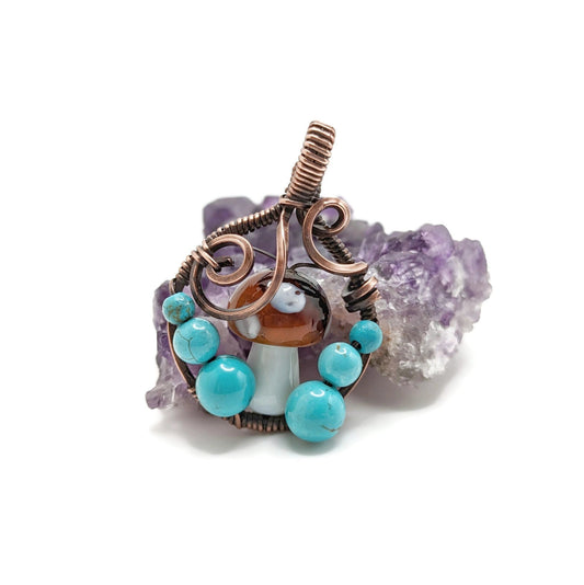 Round pendant with mushroom in the middle and bright blue turquoise howlite at its sides.